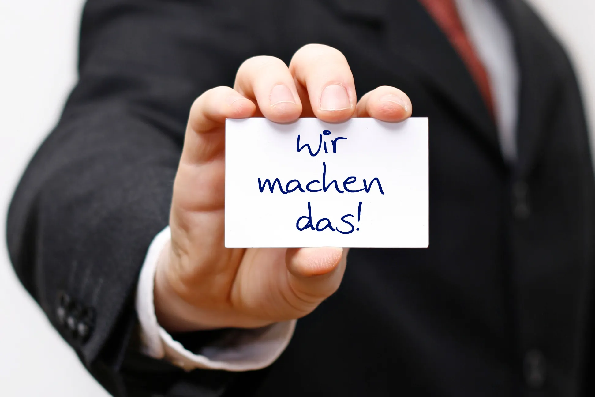 Hand hält Karte mit der Aufschrift "Wir machen das!"